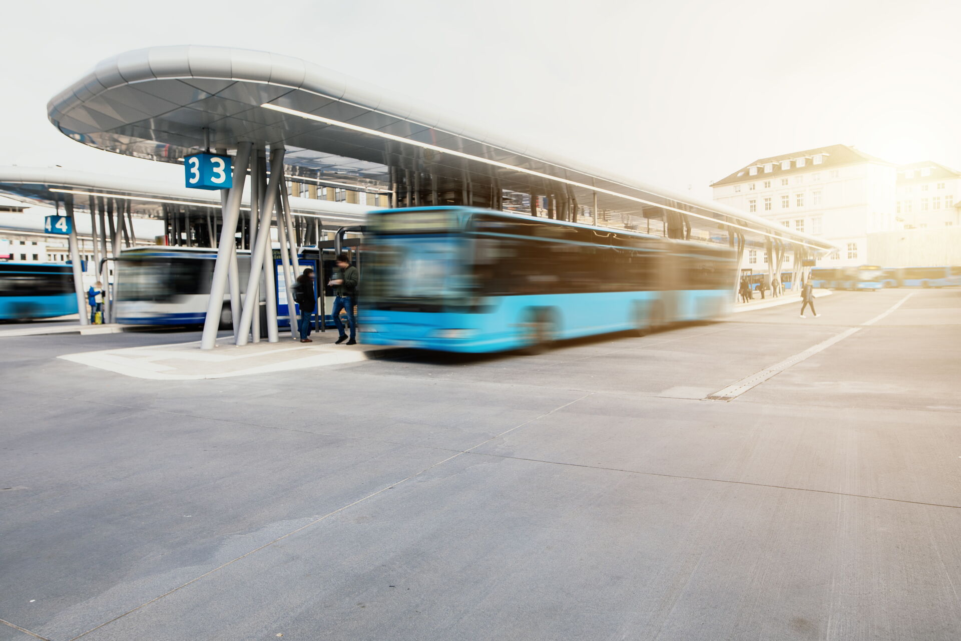 Eine Aufnahme von einem Busbahnhof, wo drei verschwommene Busse an einer Haltestellen warten
