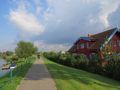 Radtour durch Kurische Nehrunf Ein Radweg an einem See führt durch eine Wohnsiedlung