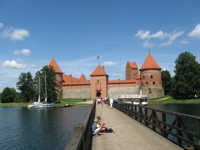 Individuelle Radtour durch das Baltikum Im Vordergrund ist eine Brücke mit Personen drauf und im Hintergrund befindet sich eine rote Burg