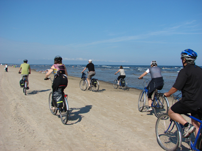 Mit dem Rad durch das gesamte Baltikum Eine Gruppe von Fahrradfahrern fährt an einem Strand durch den Baltikum