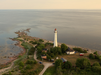 Radtour von Riga nach Tallinn Eine Luftaufnahme von einer kleinen Insel mit einem Leuchtturm, Bäumen und kleinen Wohnhäusern