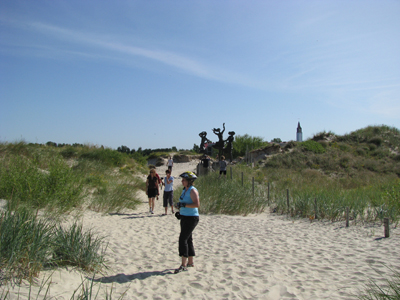 Radtour von der Kurischen Nehrung nach Masuren Eine Frau mit Fahrradhelm steht im Sand und schaut sich die Natur an. Im Hintergrund sind Menschen zu sehen