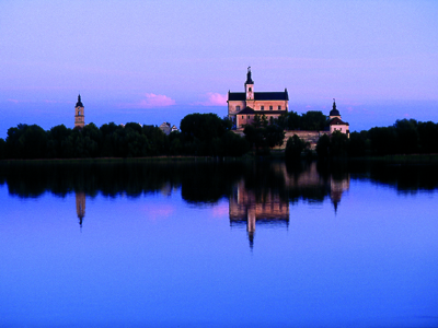 Green-Velo-Radweg in den masuren Eine Aufnahme von einem Schloss un einer Kirche bei Abenddämmerung und davor ist ein See