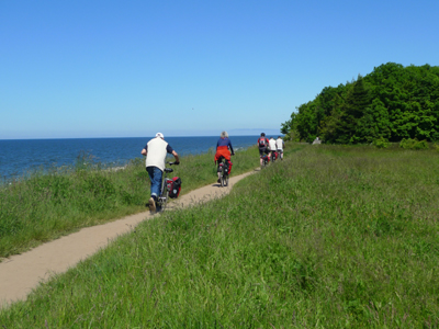 Radtour Stettin - Danzig Mehrere Fahrradfahrer fahren auf eine Radweg zwischen Wiesen und Bäumen entlang der Ostseeküste