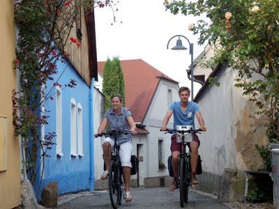 Entlang der Moldau von Budweis nach Prag Zwei Personen fahren mit dem Fahrrad in einer engen, gemütlichen Gasse