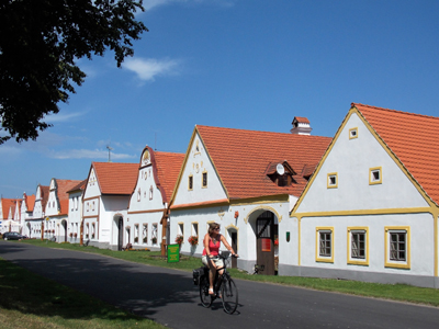 Radtour Südböhmische Perlen Eine Person fährt auf einem Radweg und im Hintergrund weiße Häuser, die fast alle gleich aussehen