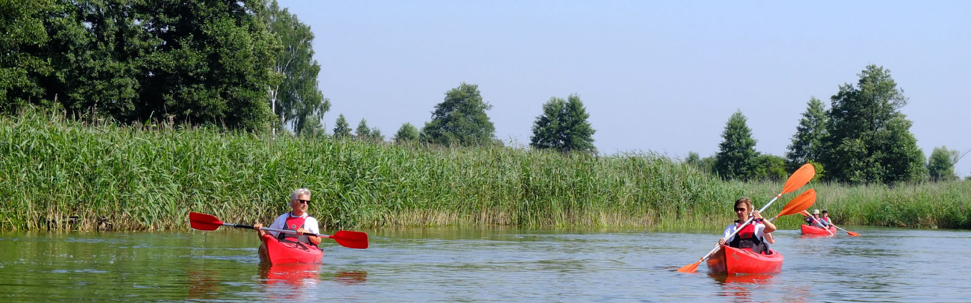 3 Personen fahren mit drei Kanus auf einem See und genießen die Natur