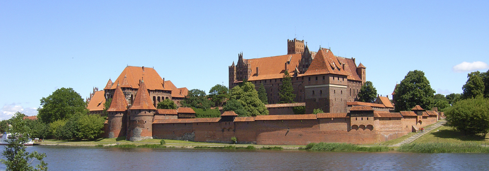 Landschaften und Städte in Polen Eine Burg aus Maurersteinen befindet sich hinter einem See