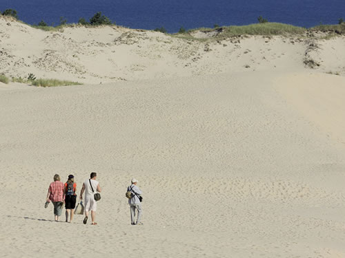 Eine Familie läuft einen großen Sandberg runter zu einem See in Polen